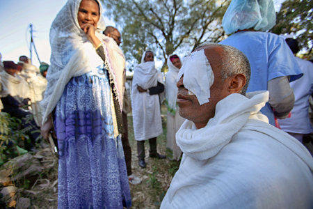 Gebretsahme WeldeSelase  is back at St. Mary's Aksum Hospital, the morning after his bilateral cataract surgery.
All patients that had surgery the day before, wait in the morning chill as doctors remove their eye patches, and observe them as they start seeing again. 
His wife, Amsale Teye, looks on in anticipation.